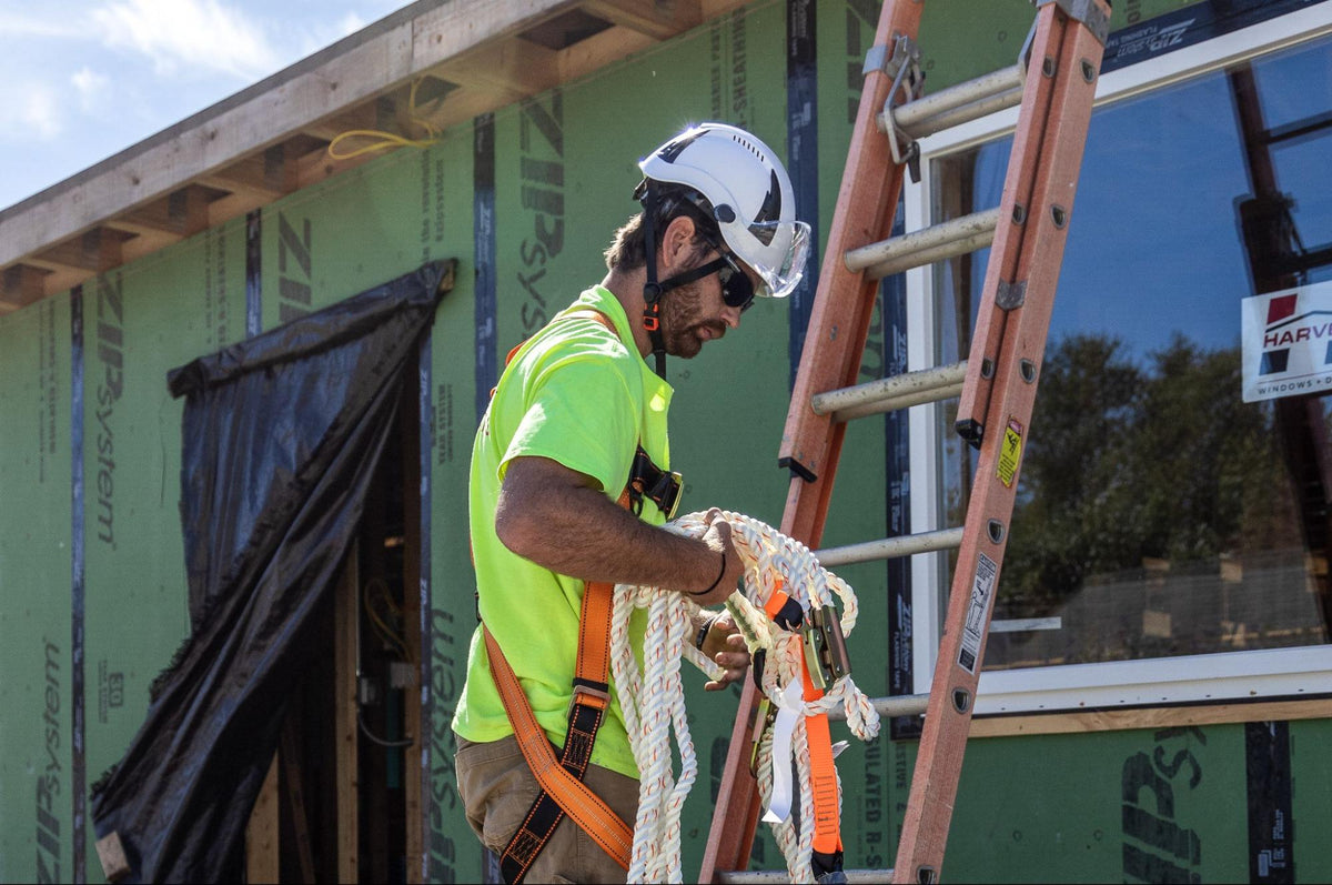 Construction worker wearing PPE holding fall protection equipment