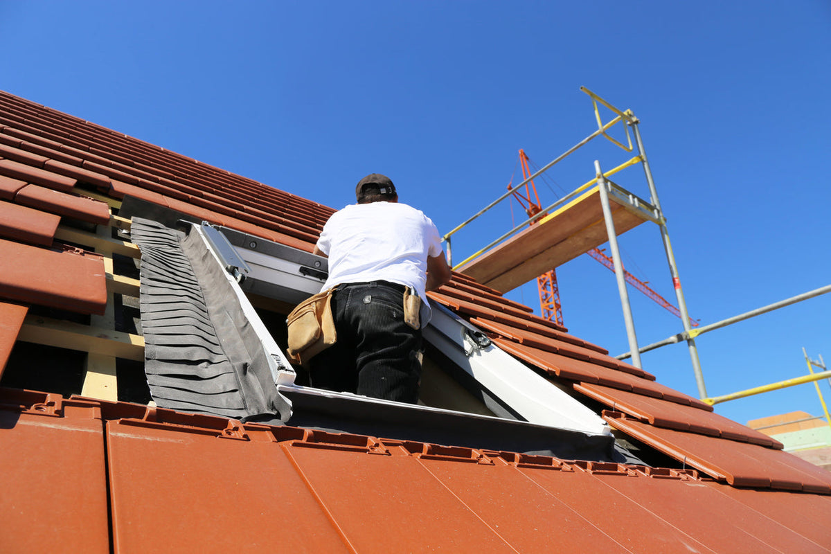 Construction worker standing in skylight on roof
