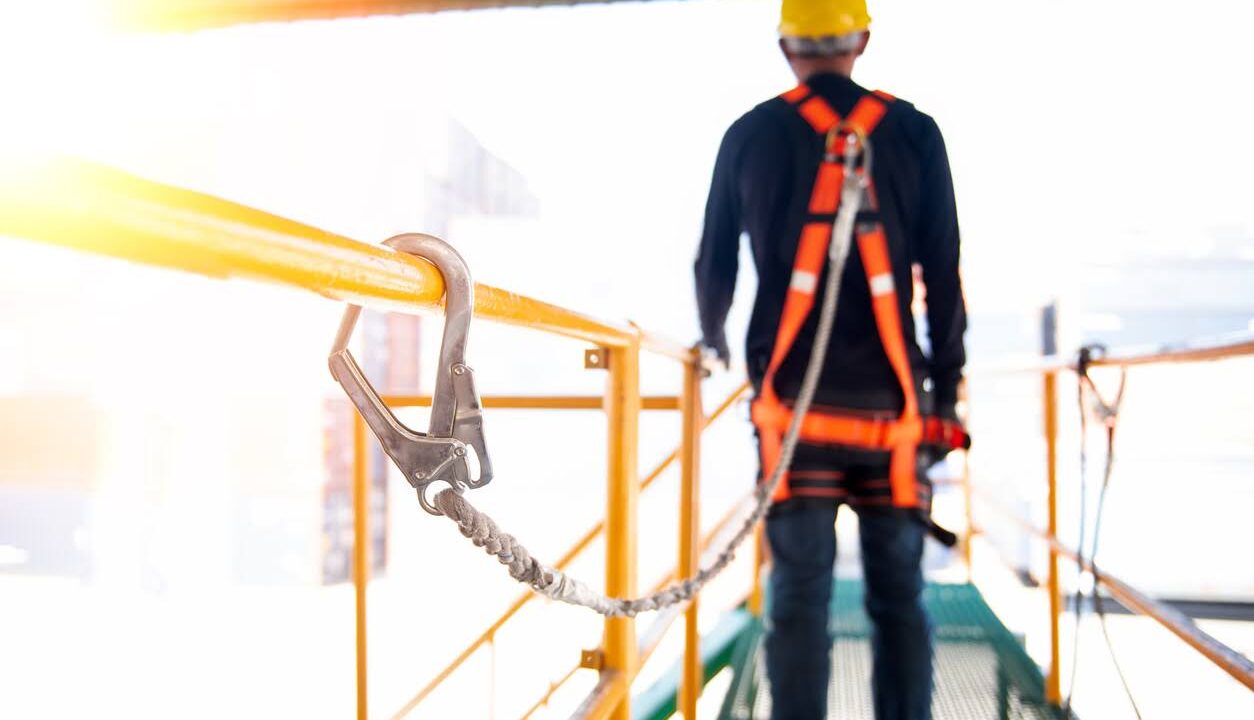 Construction worker use safety harness and safety line working on a new construction site project.