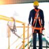 Construction worker use safety harness and safety line working on a new construction site project.