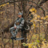 A man sitting in a tree stand wearing Malta hunting gear